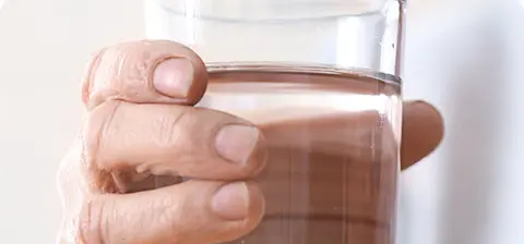 Person’s hand holding a glass of clear liquid